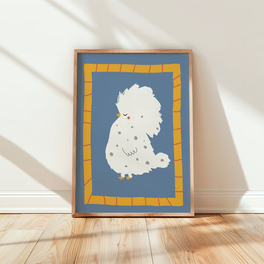 A framed art print featuring a cute white fluffy bird with gray spots on a dusty blue background, leaning against a white wall on a light wood floor.