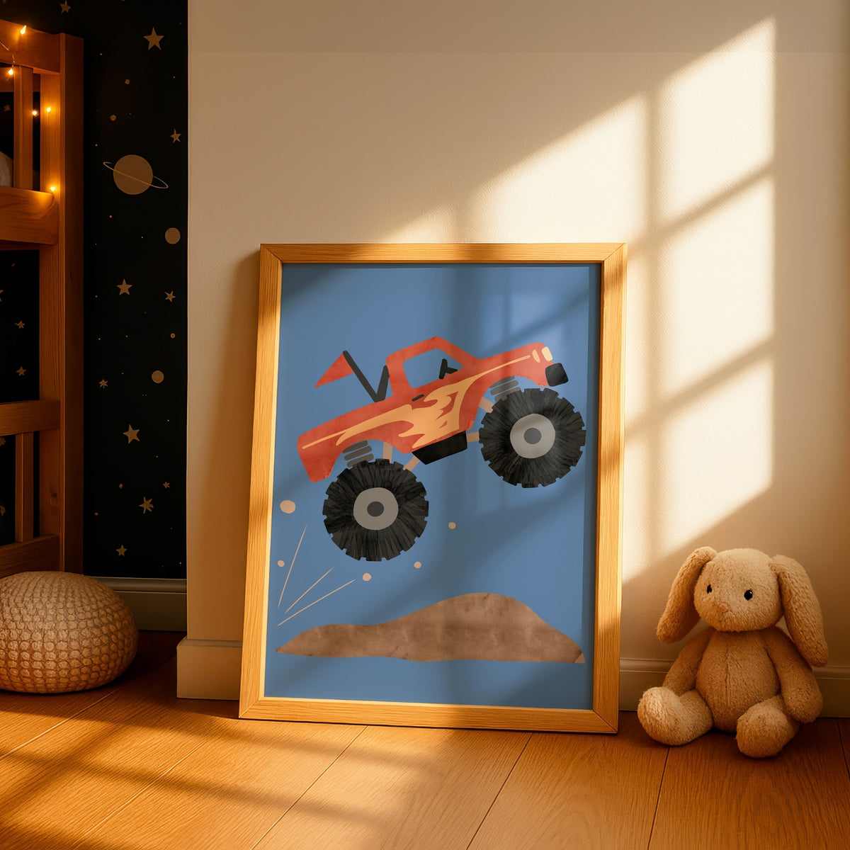 A framed children's art print featuring a red monster truck jumping over a dirt mound on a blue background, leaning against a wall in a sunlit nursery next to a stuffed bunny.