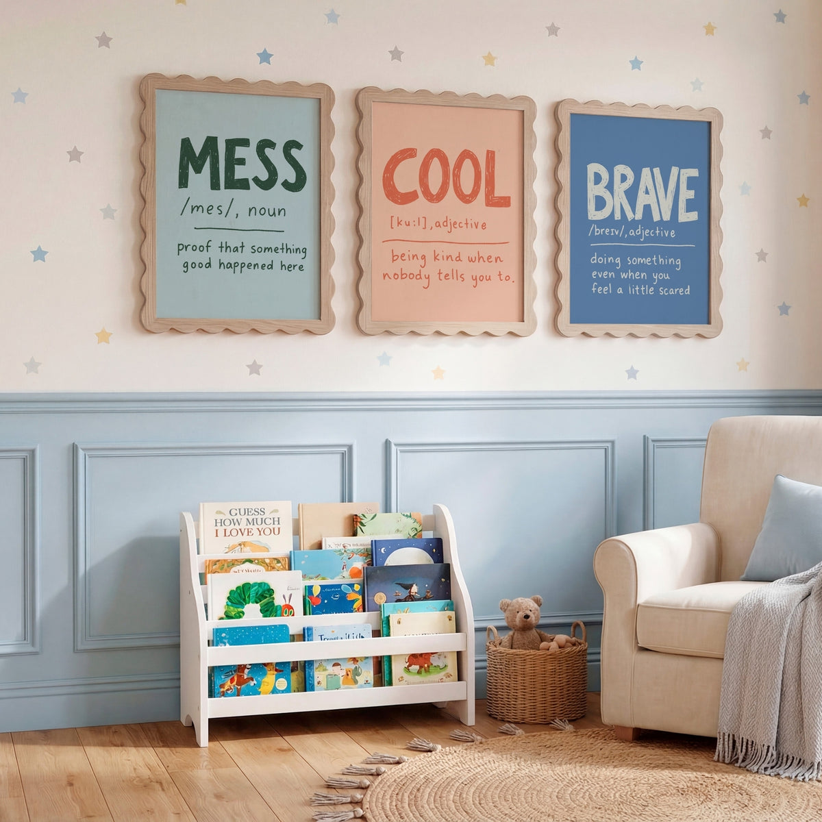 Three framed nursery wall art prints with words 'MESS', 'COOL', and 'BRAVE' hang above a white children's book rack in a styled nursery room with a cream armchair, blue wainscoting, and star decals.