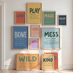 A gallery wall arrangement of multiple framed motivational and educational posters with colorful text and wood frames, displayed on a white wall in a bright room.
