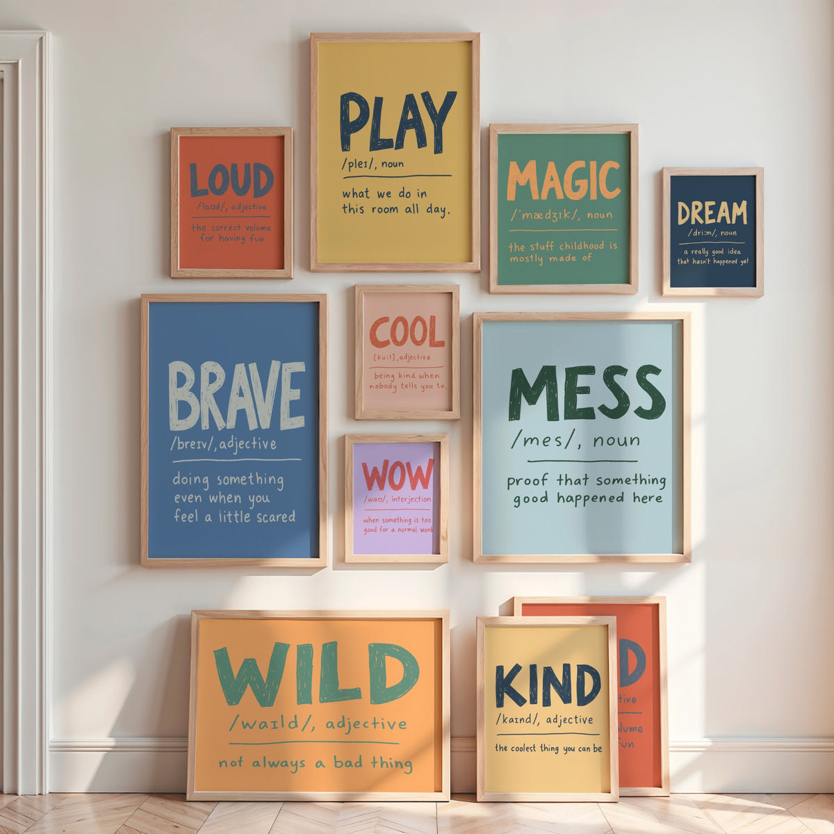 A gallery wall arrangement of multiple framed motivational and educational posters with colorful text and wood frames, displayed on a white wall in a bright room.