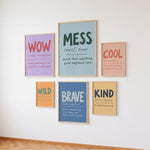 Six framed typography wall art prints with colorful educational-style words and definitions, arranged on a white wall above a wood floor.
