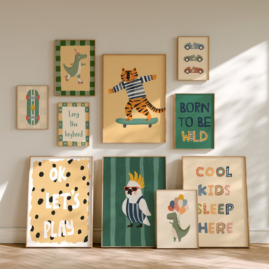 A gallery wall display of nine framed children's art prints with playful illustrations and text, arranged on a light beige wall above a wood floor.