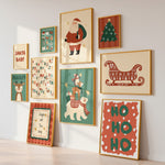 A set of nine framed Christmas-themed art prints arranged in a gallery wall on a white wall above a light wood floor. The prints feature vintage-style illustrations including Santa Claus, Rudolph the Red-Nosed Reindeer, a Christmas tree, a sleigh, polar bears, reindeer, and holiday text like 'Santa Baby', 'Ho Ho Ho', and 'Jingle All The Way'.