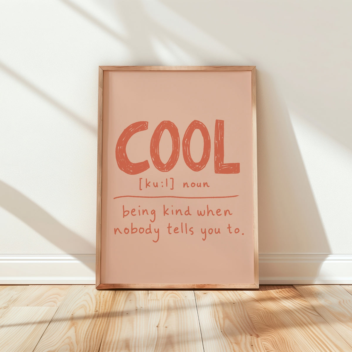 Cool definition print in terracotta on blush with phonetics and kindness quote, framed in oak on wood floor