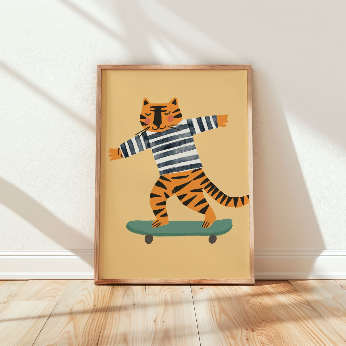 A framed art print featuring a cartoon tiger in a black and white striped shirt balancing on a green skateboard, leaning against a white wall on a light wood floor.