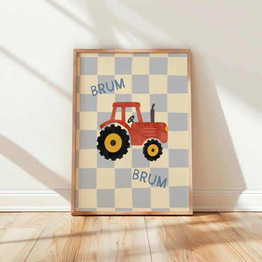 A framed children's wall art print featuring a red tractor on a cream and light gray checkerboard background with the word 'BRUM' repeated in blue. The framed print is leaning against a white wall on a light wood floor.