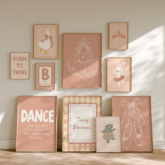 A coordinated set of framed nursery wall art prints arranged on a beige wall above a light wood floor. The prints feature ballet-themed illustrations and text, including a ballerina, bunny in tutu, ballet shoes, tiara, duck, and phrases such as 'BORN TO TWIRL' and 'DANCE is the closest thing to magic.