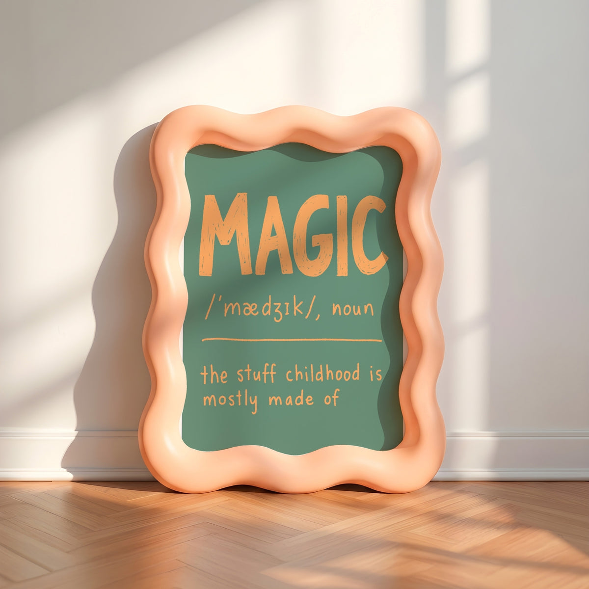 A decorative framed sign leaning against a wall on a wood floor, with a peach wavy frame and a green center that reads “MAGIC / ‘médÙÙk/, noun / the stuff childhood is mostly made of” in warm yellow text.