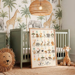 A framed alphabet and safari animal nursery art print leaning against a sage green crib in a styled nursery room. The print features colorful illustrations of letters, animals, and trees.