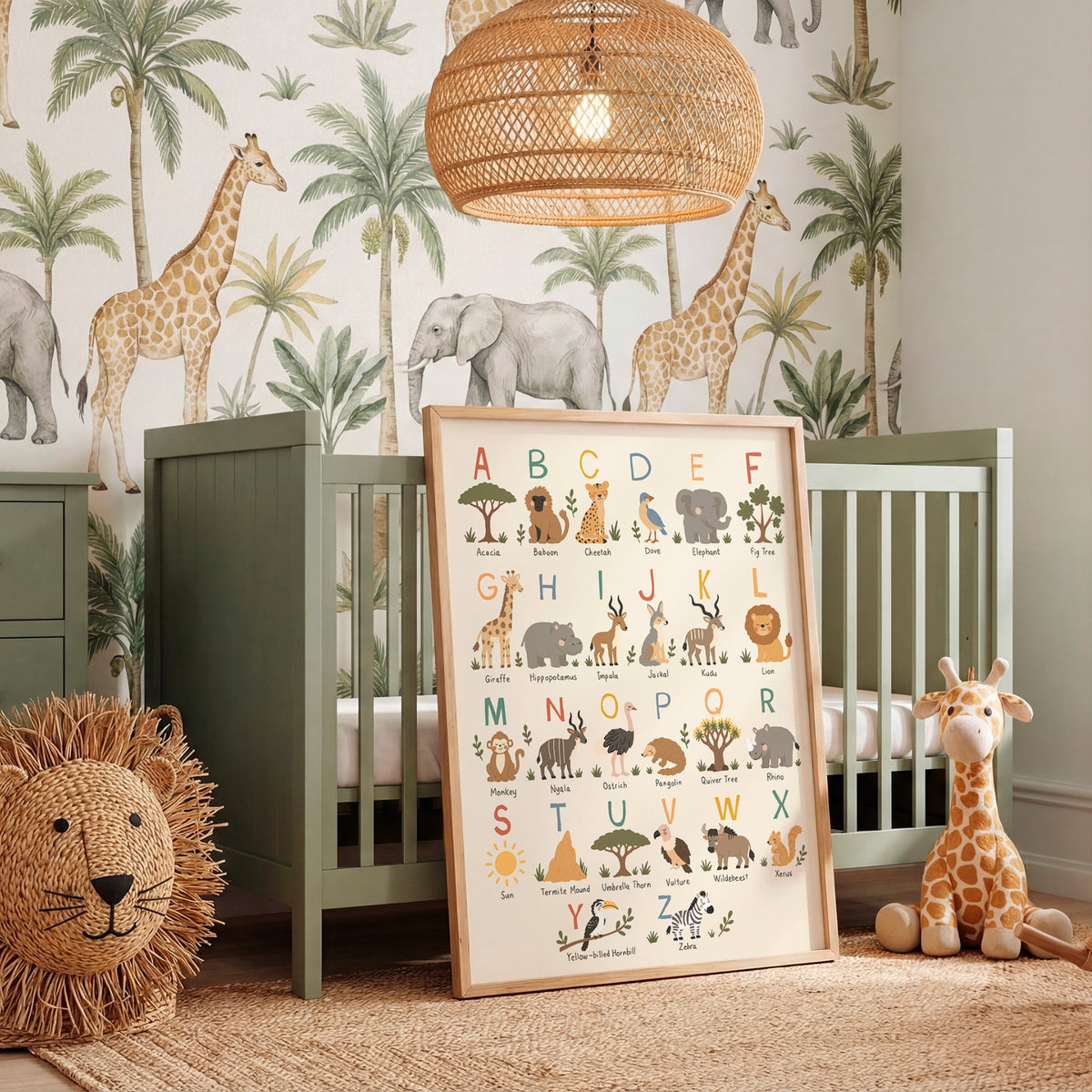 A framed alphabet and safari animal nursery art print leaning against a sage green crib in a styled nursery room. The print features colorful illustrations of letters, animals, and trees.