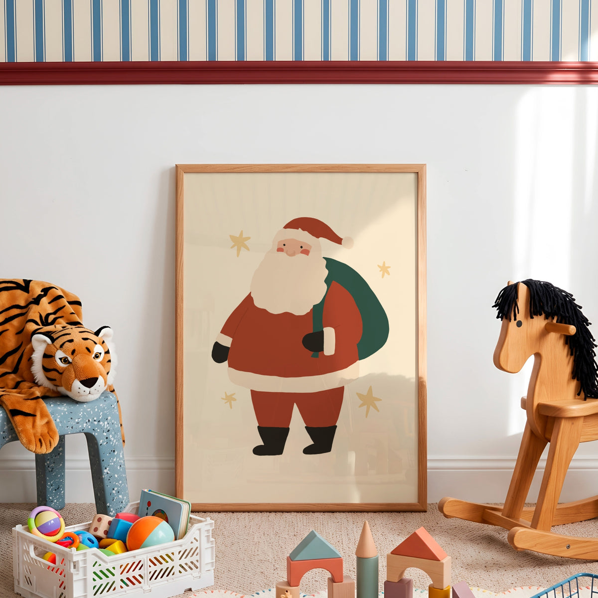A framed art print of a cartoon Santa Claus standing on a beige floor in a styled children's room. The print features Santa in his classic red suit with a white beard and black boots, holding a green sack.