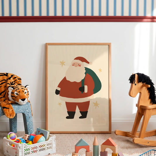 A framed art print of a cartoon Santa Claus standing on a beige floor in a styled children's room. The print features Santa in his classic red suit with a white beard and black boots, holding a green sack.