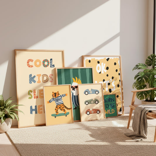 A styled collection of seven framed kids' art prints with various colorful illustrations and text, arranged on a beige rug in a sunlit room next to a wooden chair and potted plants.