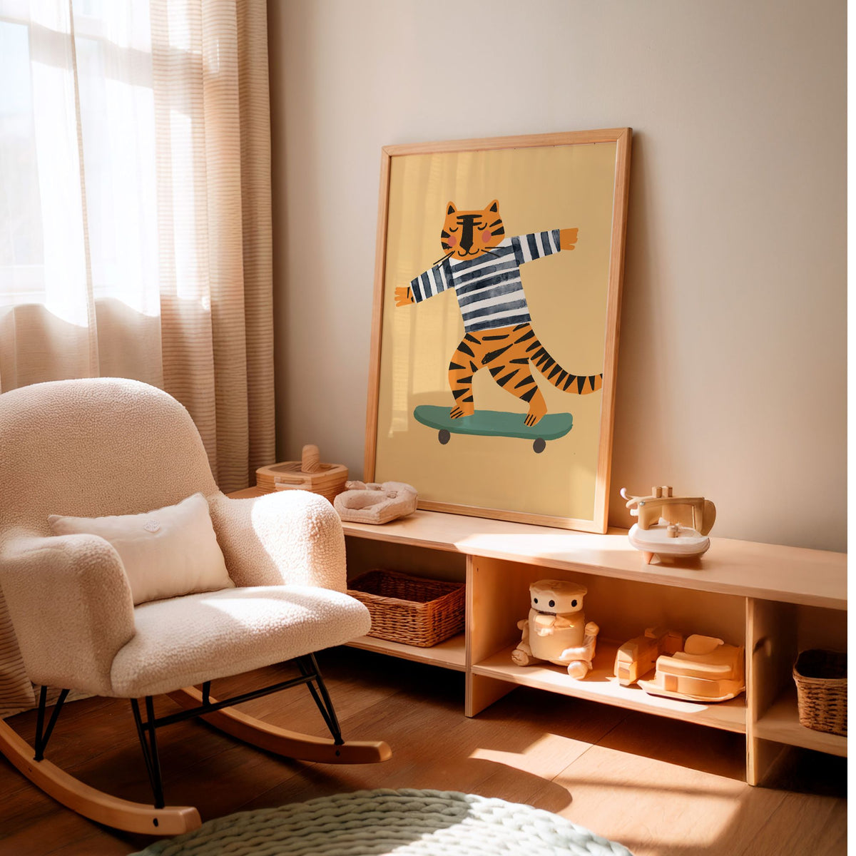 A framed art print featuring a cartoon tiger in a blue and white striped shirt riding a teal skateboard, displayed on a light wood console in a warm, sunlit nursery room next to a cream-colored rocking chair.