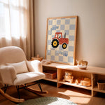 A framed nursery wall art print featuring a red tractor on a blue and white checkerboard with the word 'BRUM' appears twice, styled in a warm, sunlit nursery next to a cream-colored rocking chair and a wooden toy shelf.