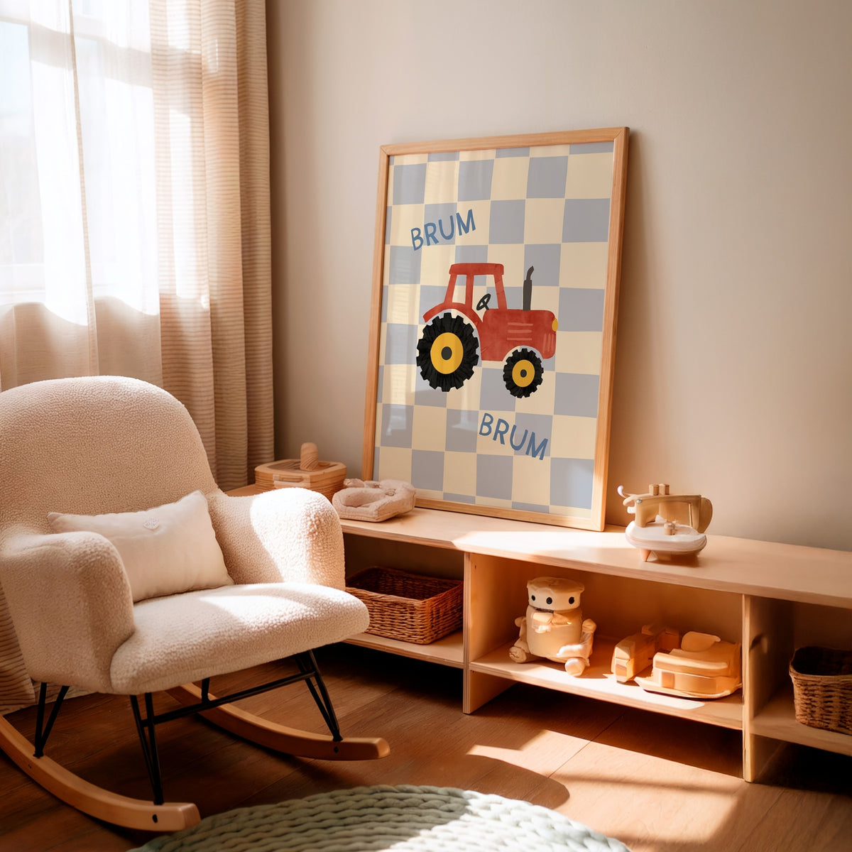 A framed nursery wall art print featuring a red tractor on a blue and white checkerboard with the word 'BRUM' appears twice, styled in a warm, sunlit nursery next to a cream-colored rocking chair and a wooden toy shelf.