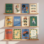 Three wooden wall shelves display a set of colorful children's art prints with motivational and nature-themed illustrations, including a dinosaur, racing cars, a tiger on a skateboard, a blue bird, and a green dinosaur.