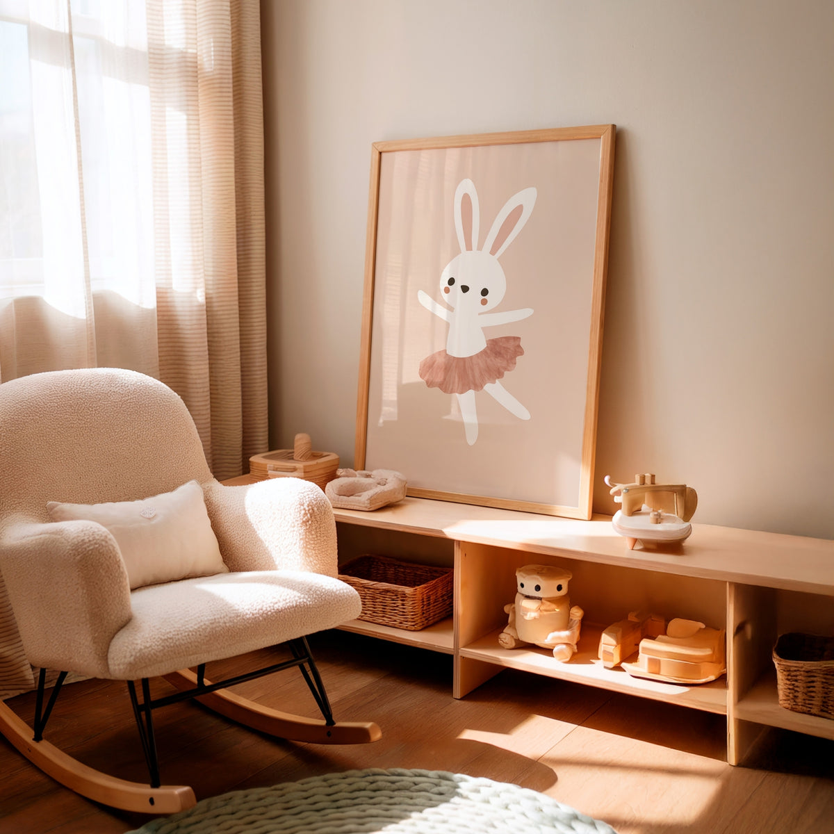 A framed nursery art print featuring a white bunny ballerina with a pink tutu, leaning against a wall on a wooden shelf in a softly lit nursery with a cream rocking chair.