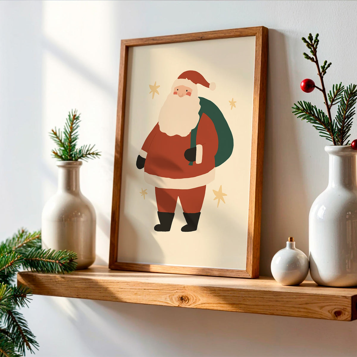 A framed art print of a cartoon Santa Claus hanging on a light-colored wall above a wooden shelf, styled with white ceramic vases, pine branches, and a small ornament.