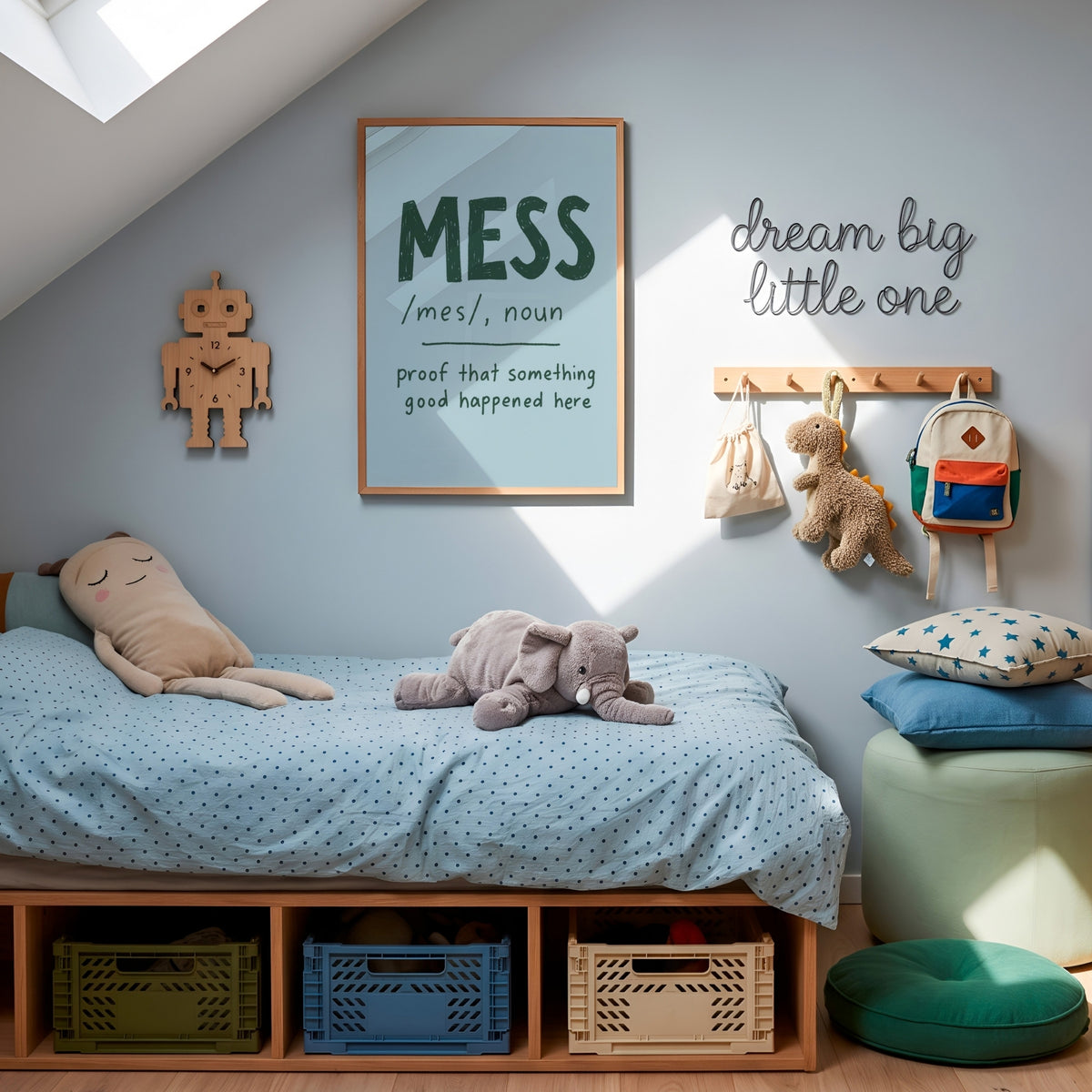 A styled children's bedroom corner with a low wooden bed frame, light blue bedding, plush toys, wall hooks, a framed word-art print reading 'MESS', a robot wall clock, and a green pouf with star pillows.