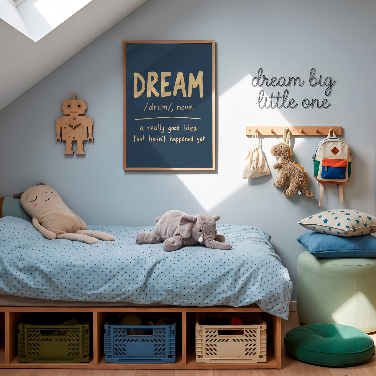 A styled children's bedroom corner with a low wooden bed, light blue bedding, plush toys, wall decor including a framed 'DREAM' sign and 'dream big little one' wall art, storage bins underneath the bed, and a mint ottoman with star pillows.