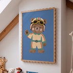 Racing bear kids print in scalloped oak frame on attic bedroom wall above teddy bears and giraffe plush