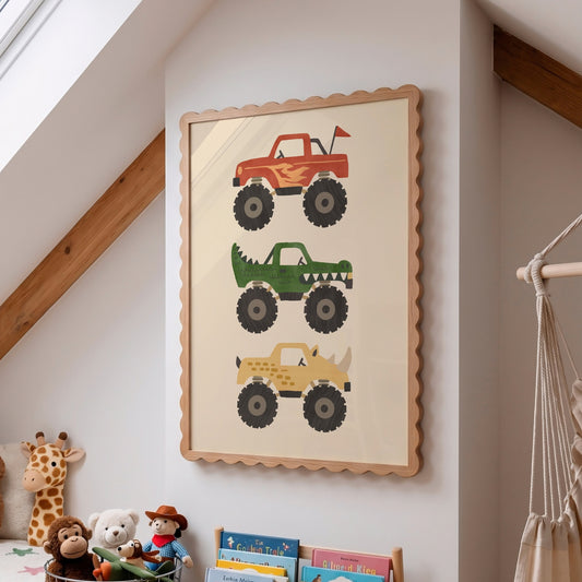 A framed wall art print featuring three monster truck illustrations in red, green, and tan, displayed on a white wall in a child's room with toys and a hammock visible.