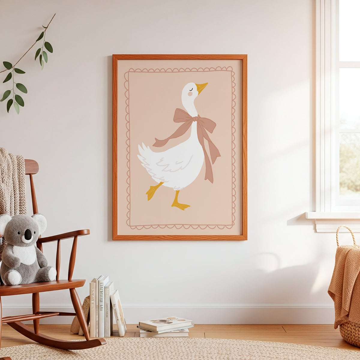 A framed art print featuring a white goose with a brown bow tie on a beige background, hanging on a white wall in a styled nursery room with a wooden rocking chair, books, and a window.