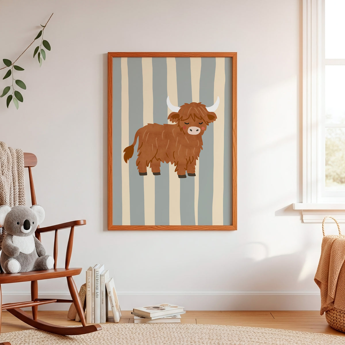 A framed vertical art print featuring a cartoon Highland cow on a striped background, displayed on a white wall in a styled children's room with a rocking chair, books, and a window.