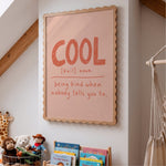 Cool definition print in scalloped oak frame above kids bookshelf with teddy bears and hanging chair