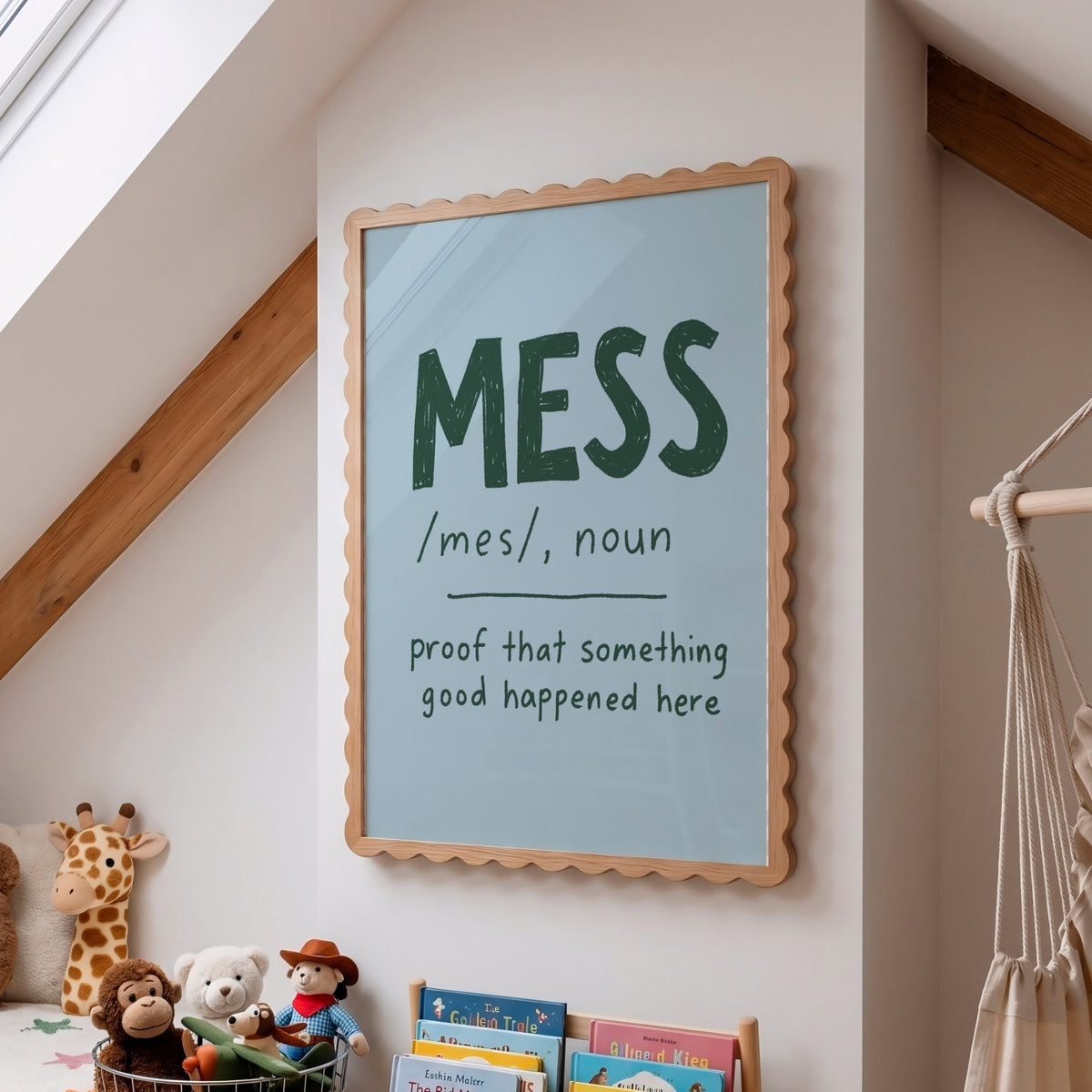 A framed wall art print with a scalloped wood frame hangs on a white wall in a child's room. The print has a pale blue background with the word 'MESS' in large dark green letters and a dictionary-style definition below.