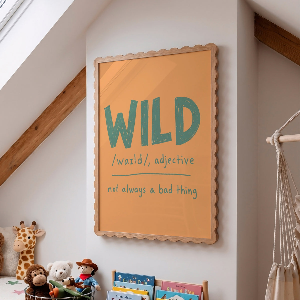 A framed wall art print with a scalloped wooden frame hangs on a white wall in a child's room. The print features the word 'WILD' in large teal letters with a dictionary-style definition underneath: '/wazld, adjective not always a bad thing'.