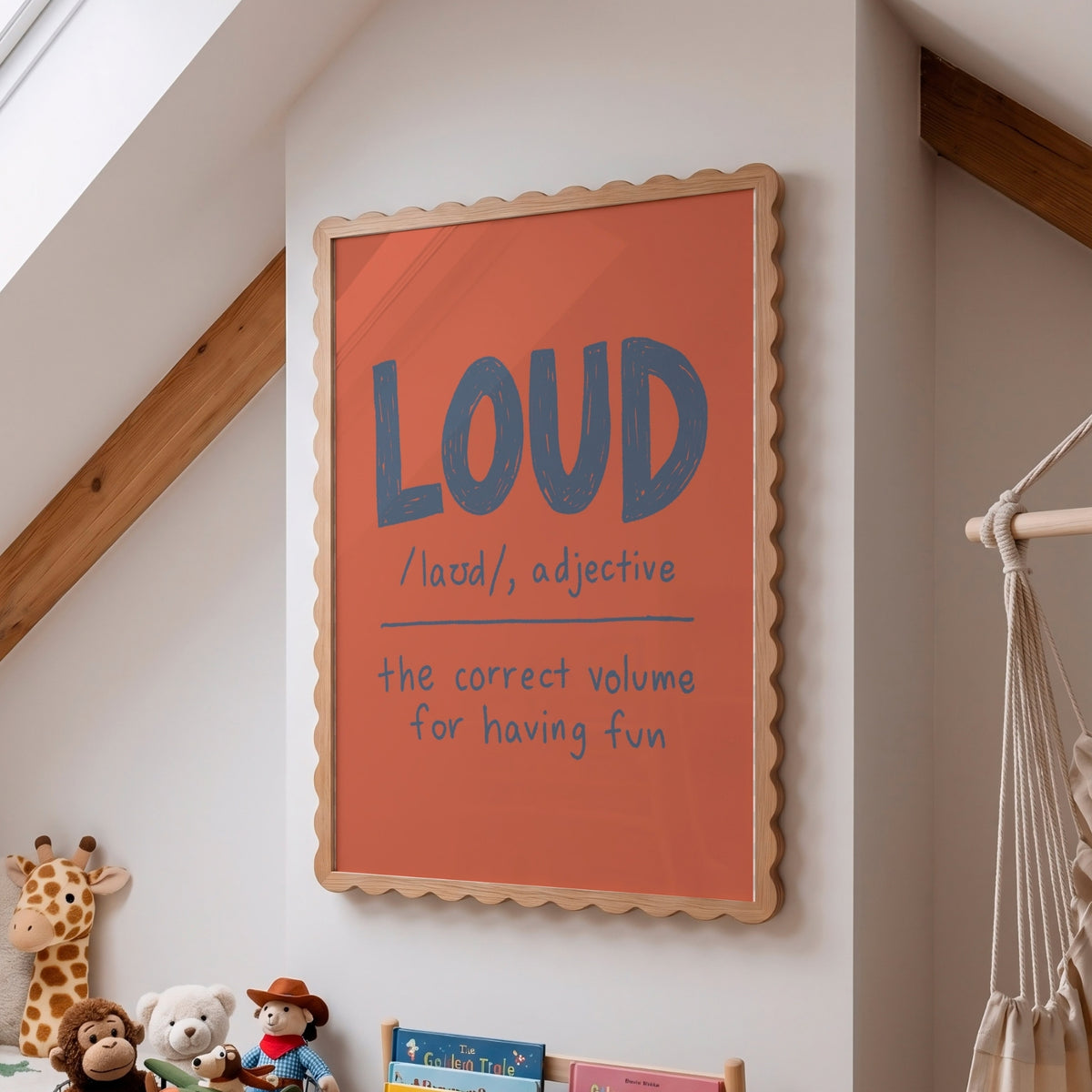 A framed wall art print with a warm orange background and scalloped light wood frame, featuring the word 'LOUD' in large blue letters with pronunciation and definition text below, shown hanging on a white wall in a child's room.