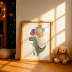 A framed children's wall art print leaning against a wall in a sunlit nursery. The print shows a green dinosaur holding a cluster of pastel balloons.