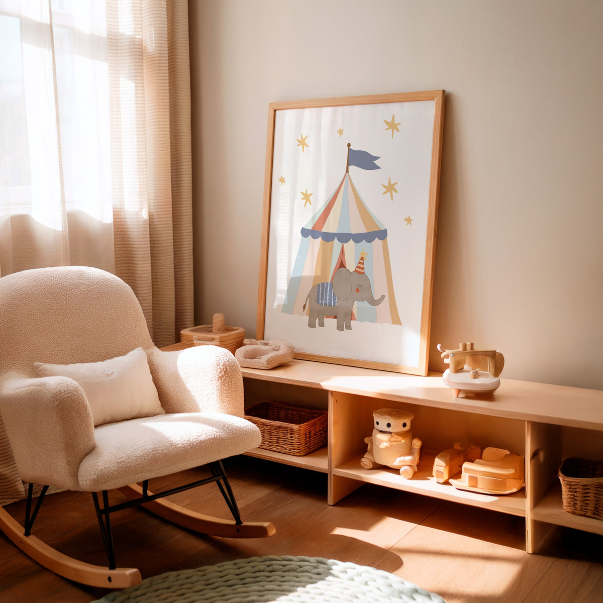 A nursery corner with a cream boucle rocking chair beside a light wood console shelf holding toys, with a framed circus-themed print leaning against the wall.