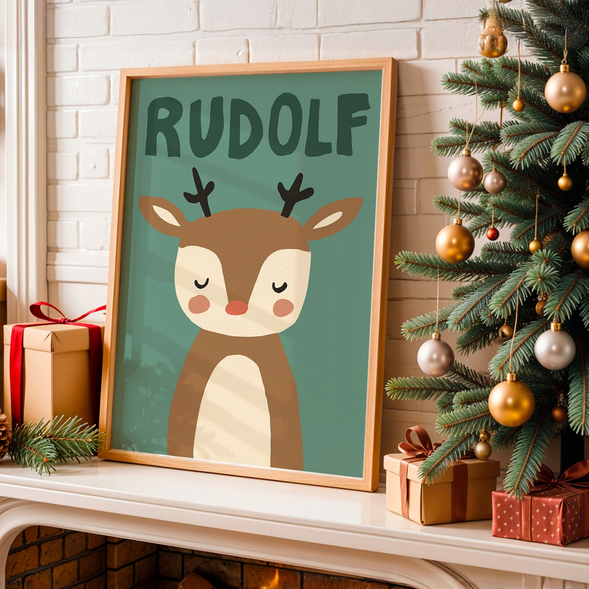 A framed personalized Christmas art print featuring a cute cartoon reindeer with the name 'RUDOLF' above it, displayed on a fireplace mantel next to a decorated Christmas tree and wrapped gifts.