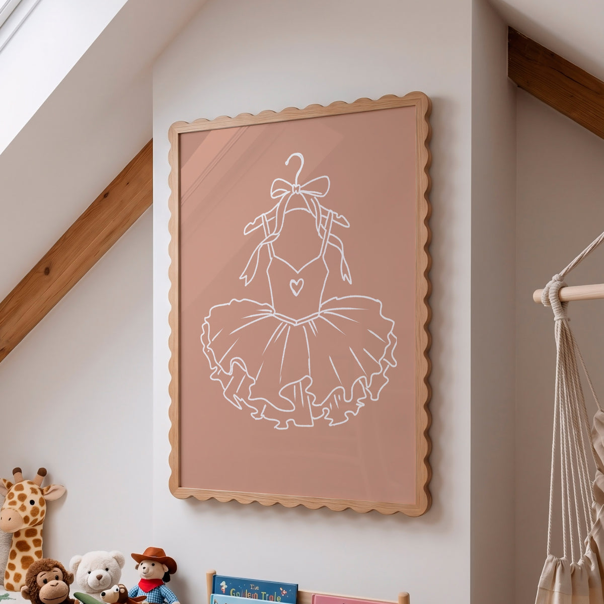A framed wall art print featuring a white line drawing of a ballerina tutu on a dusty pink background, styled in a child's bedroom with wooden beams, a macrame hanger, and stuffed animals.