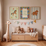A styled children's nursery interior with three framed animal-themed wall prints above a wooden storage bench. The prints show a horse, a flower-bordered sign reading 'LITTLE WILD FLOWER,' and a cow.