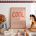A framed art print with the word 'COOL' and a dictionary definition, styled in a child's playroom with toys, a rocking horse, and a stuffed tiger.