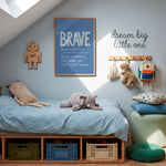 A styled children's bedroom corner with a low wooden bed, light blue bedding, stuffed toys, wall hooks, a framed 'BRAVE' poster, and a green pouf on a wood floor under a slanted roof.