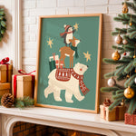A framed Christmas art print featuring a polar bear, deer, and penguin wearing red scarves and hats on a teal background, displayed on a fireplace mantel next to a decorated Christmas tree and wrapped gifts.