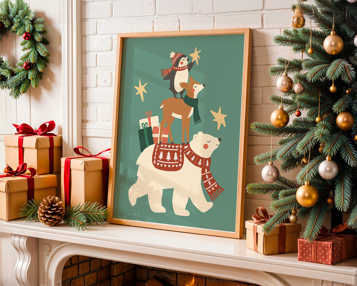 A framed Christmas art print featuring a polar bear, deer, and penguin wearing red scarves and hats on a teal background, displayed on a fireplace mantel next to a decorated Christmas tree and wrapped gifts.