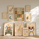 A set of framed children's wall art prints arranged on a wall and floor in a styled nursery setting. The prints feature safari-themed illustrations including an elephant, lion, giraffe, cheetah, zebra, sun, trees, and text phrases like 'Stay and see,' 'Stay curious,' 'Peace and love,' and 'BORN TO BE WILD.