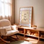 A framed nursery art print leaning on a wooden shelf in a softly lit nursery. The print reads 'you are Magic' in black script with small yellow stars, surrounded by a pale blue and white diamond pattern and a light wood frame.