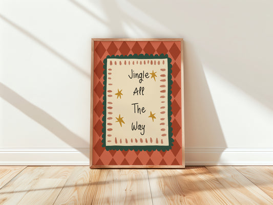 A framed holiday art print leaning against a white wall on a light wood floor. The print features the text 'Jingle All The Way' in a playful handwritten font, surrounded by a cream center panel with a dark green scalloped border, yellow stars, and a terracotta orange diamond-patterned frame.
